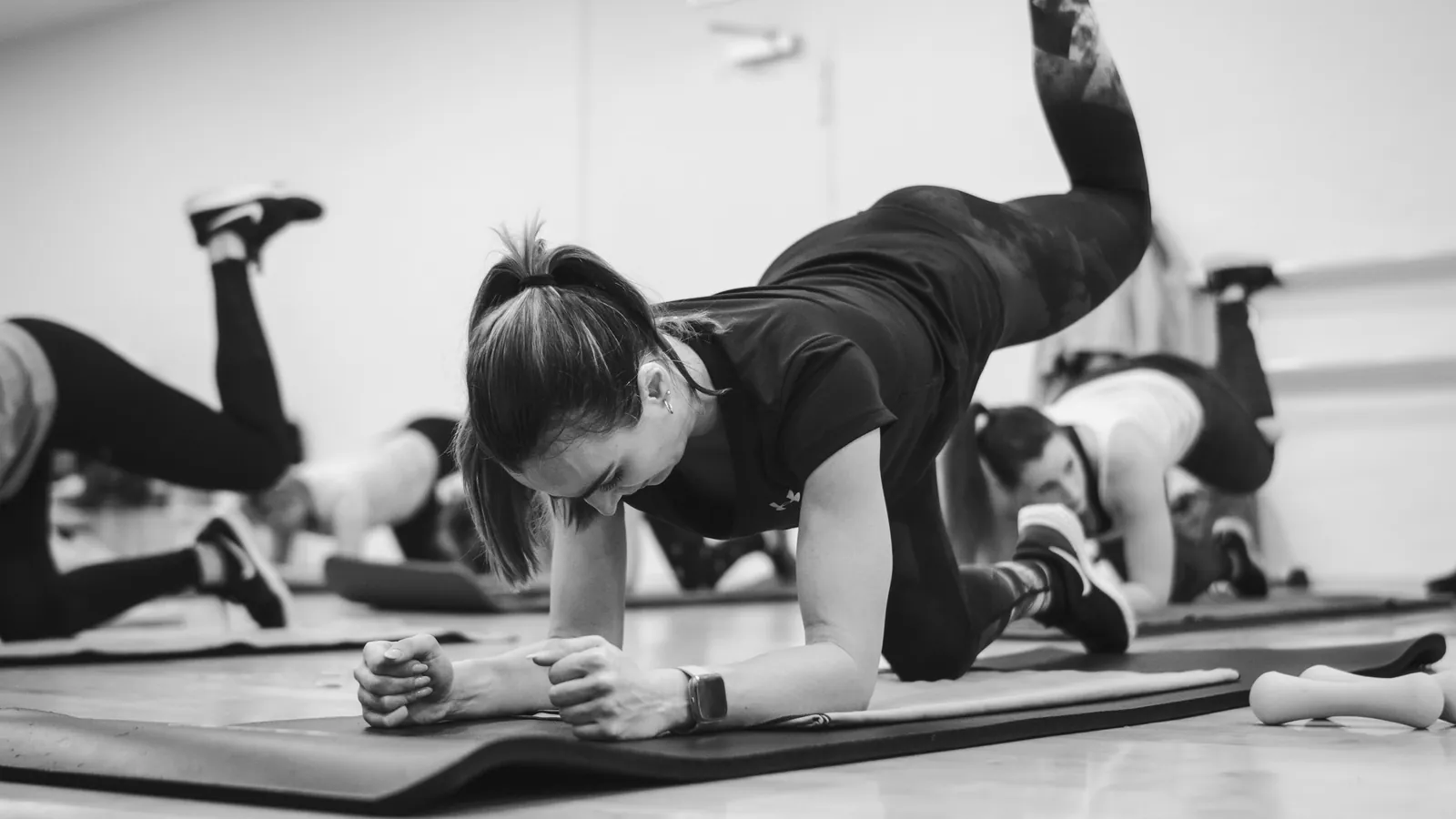 Groupe de pratiquants en gainage sur tapis, encadré en salle